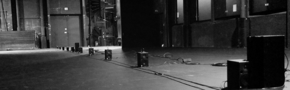 loudspeakers on a line in a darkly lit room
